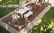 The image is taken from an aerial view, showing an outdoor seating area. There is a deck that is embedded in a gravel area, surrounded by grass.